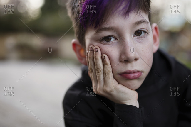Young boy resting face in palm of his hand with dirty fingernails