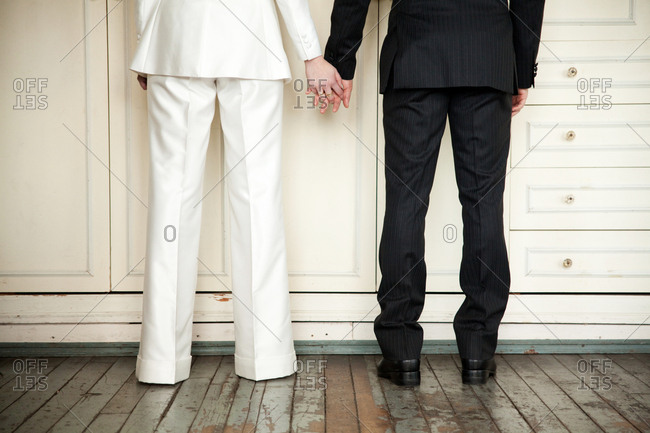 Waist-down show of a couple holding hands on their wedding day