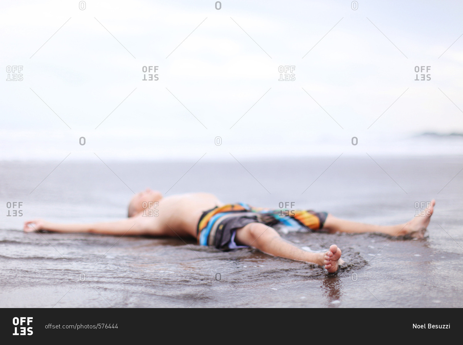 Мальчишка лежит на пляже
