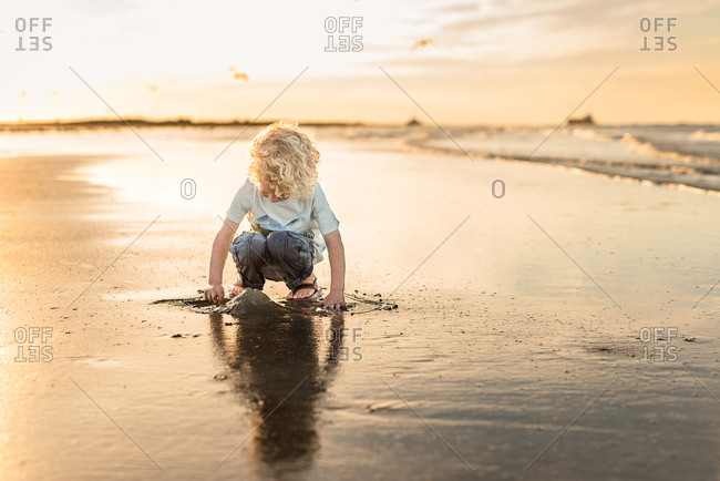 Boy building sandcastle on beach at sunset in Galveston, Texas