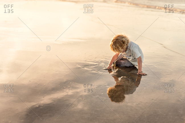 Little boy playing in water on beach at sunset in Galveston, Texas