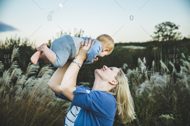 Woman lifting baby in the air outdoors