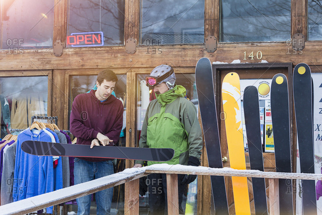 Male ski shop employee helping male customer with ski purchase