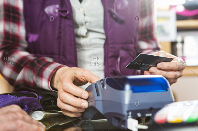 Female ski shop employee ringing up customer purchase on credit card device