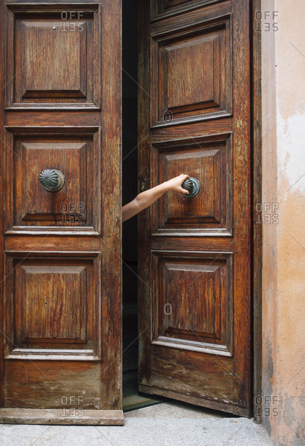 Beautiful wooden door with arm of a kid reaching out to pull it open.