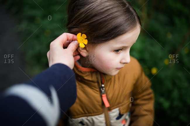 Woman putting flower in daughters hair stock photo - OFFSET