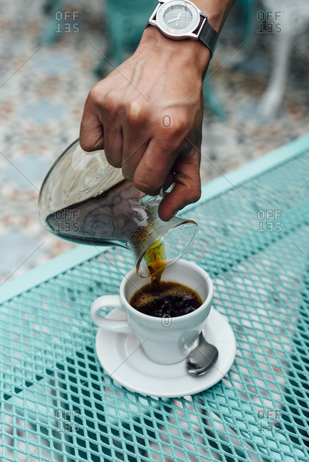 Man serving a cup of coffee from a glass coffee jug in Bogota, Colombia