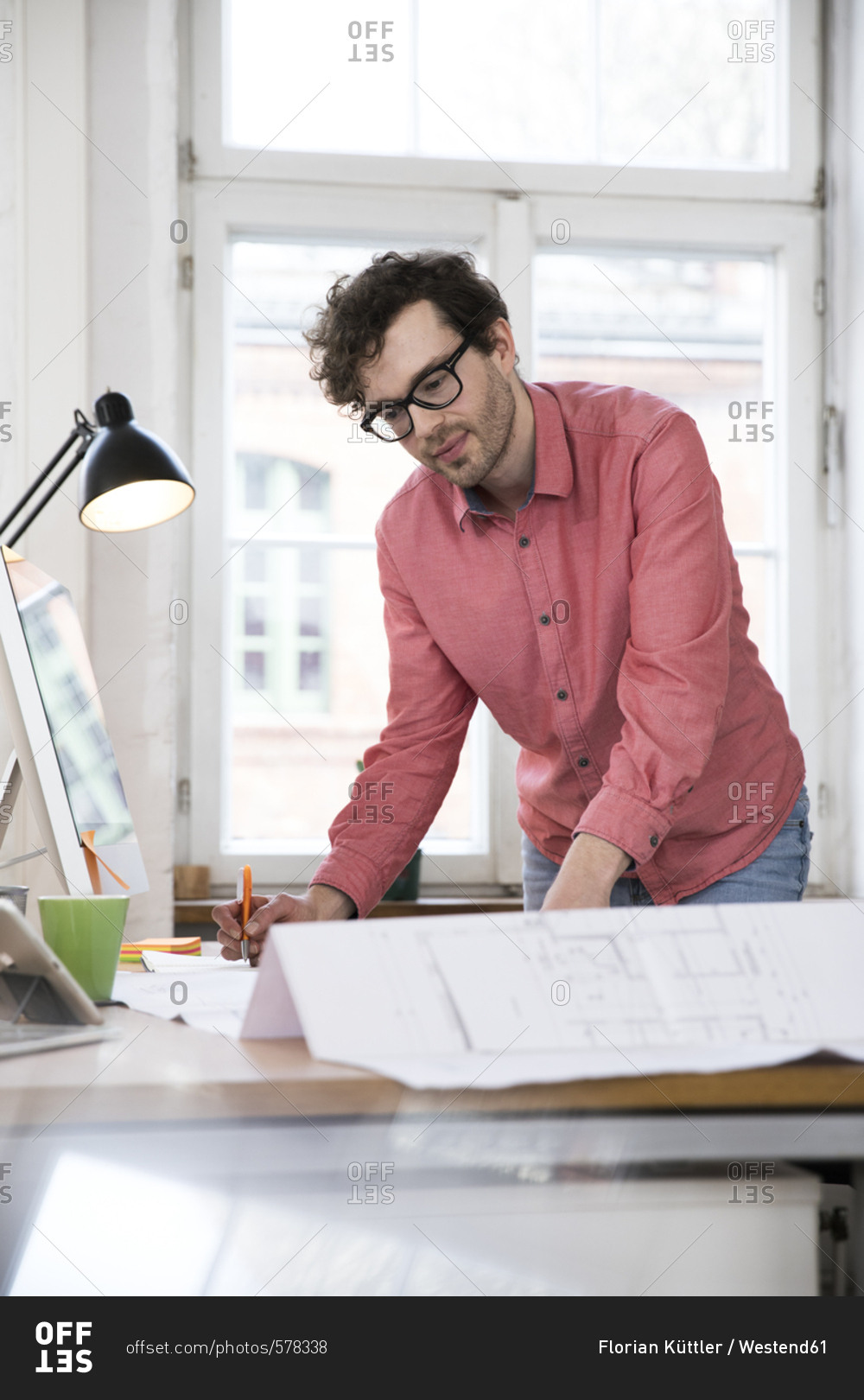 Man working on blueprint at desk in office