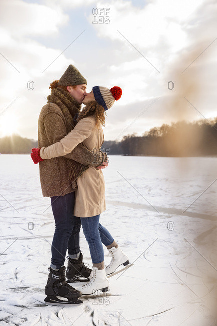Couple with ice skates kissing on frozen lake