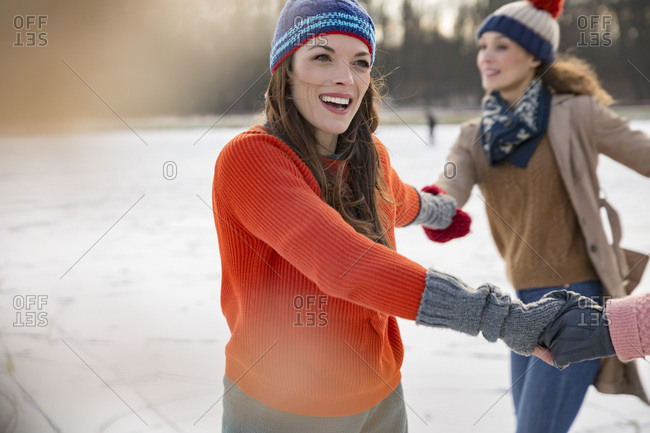 Female friends ice skating in a circle on frozen lake