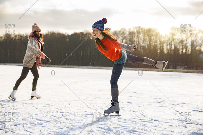 Two women ice skating on frozen lake