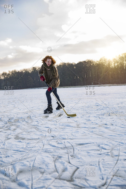 Man playing ice hockey on frozen lake