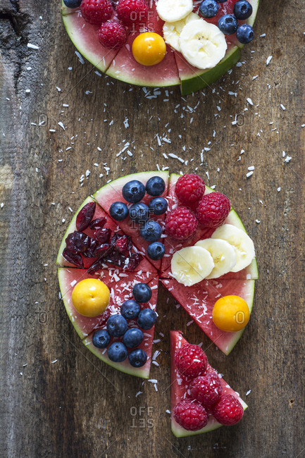 Fruitcake made of watermelon garnished with various fruits sprinkled with coconut flakes