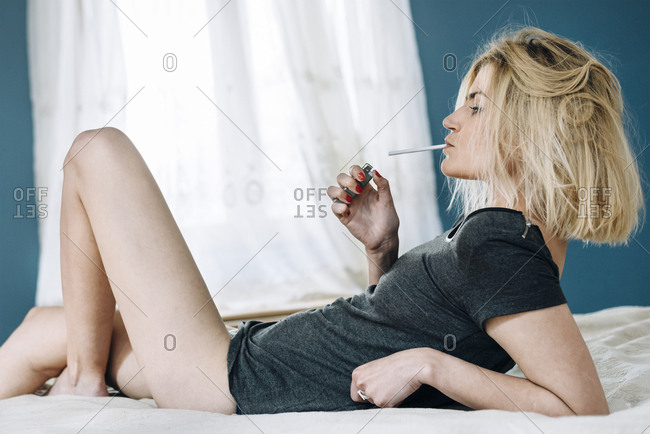 Young woman smoking in bed