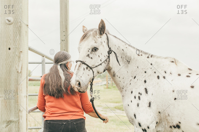 Woman walking with spotted horse