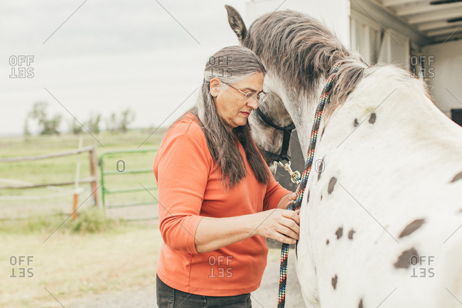 Woman tying lead rope onto a horse's neck