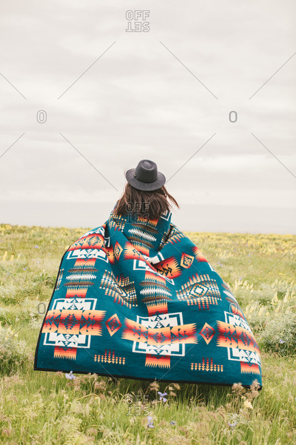 Woman wrapped in a colorful woven blanket in field