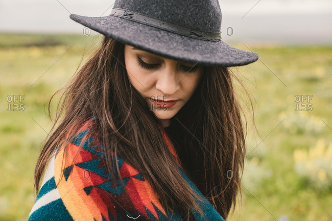 Woman looking down while wearing a western hat and woven blanket