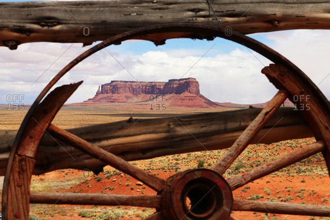 An old wagon wheel frames distant Sentinel Mesa.