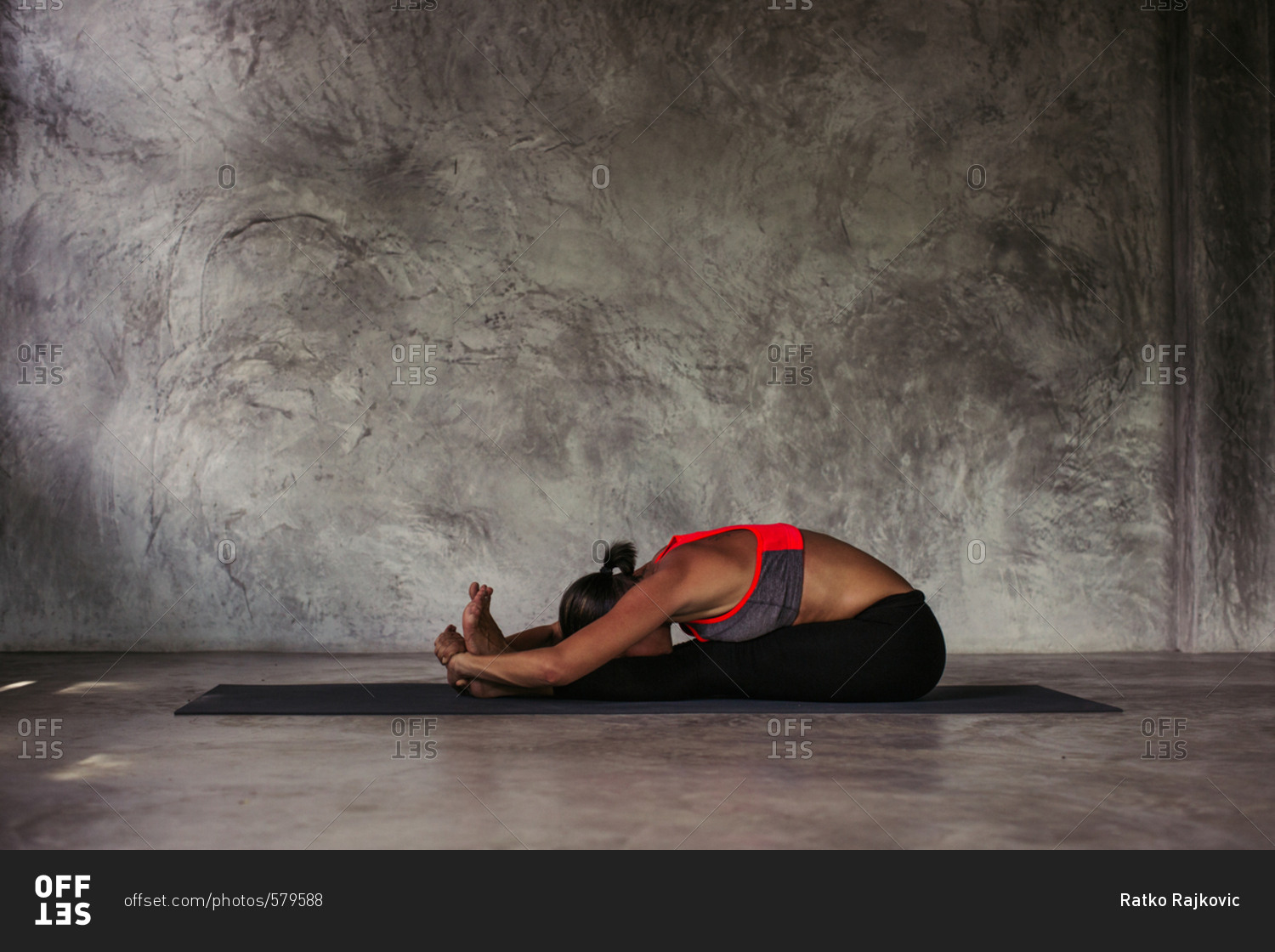 Woman practicing a seated forward fold yoga position