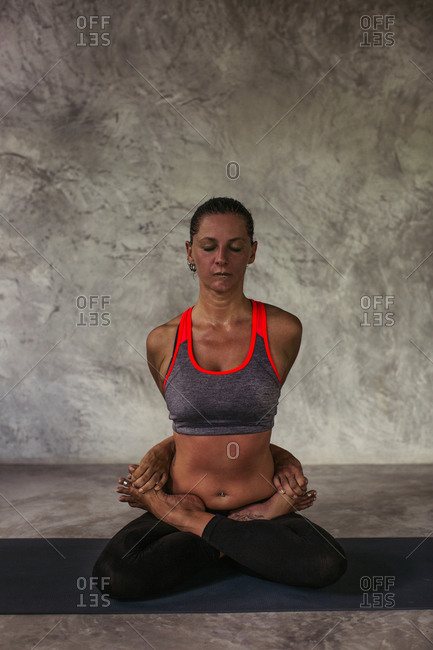 Woman in a side angle yoga pose clasping her hands behind her back stock  photo - OFFSET