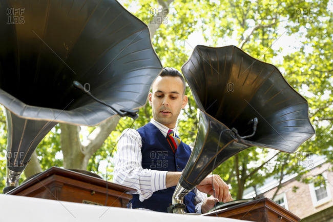 New York City, United States - June 10, 2017: 1920's Jazz Age Lawn Party at Governors Island, Man playing music on a vintage phonograph at a party