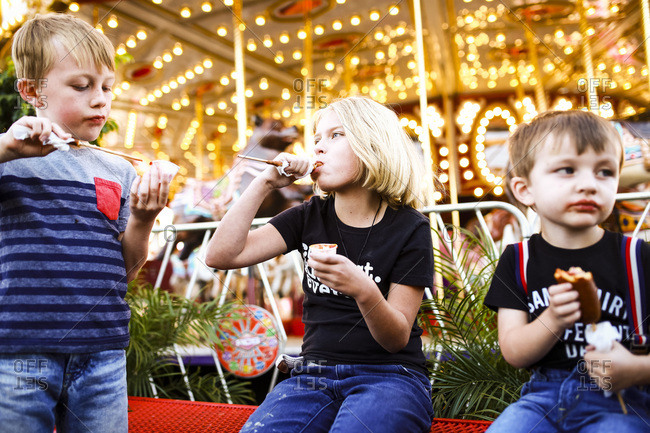 Kids eating corn dogs by a carousel