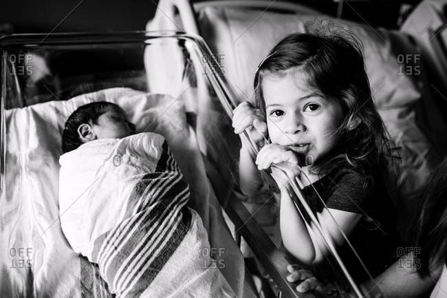 Sister looking into hospital bassinet at baby sister