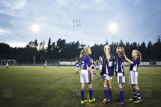 Girls standing on soccer field against sky