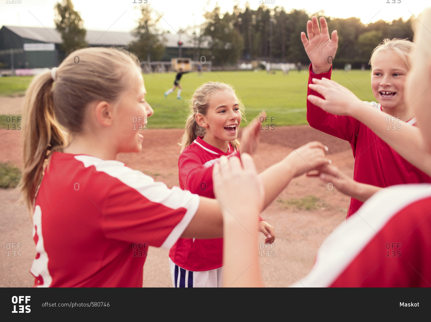 Playful female soccer players standing against field