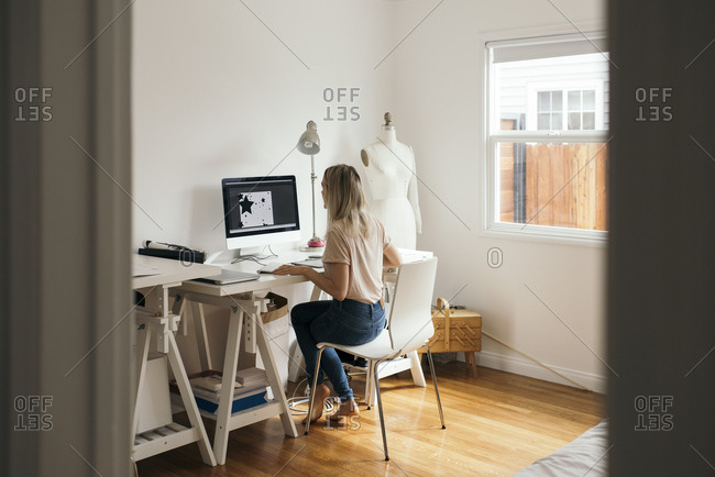 Full length rear view of graphic designer using computer at home