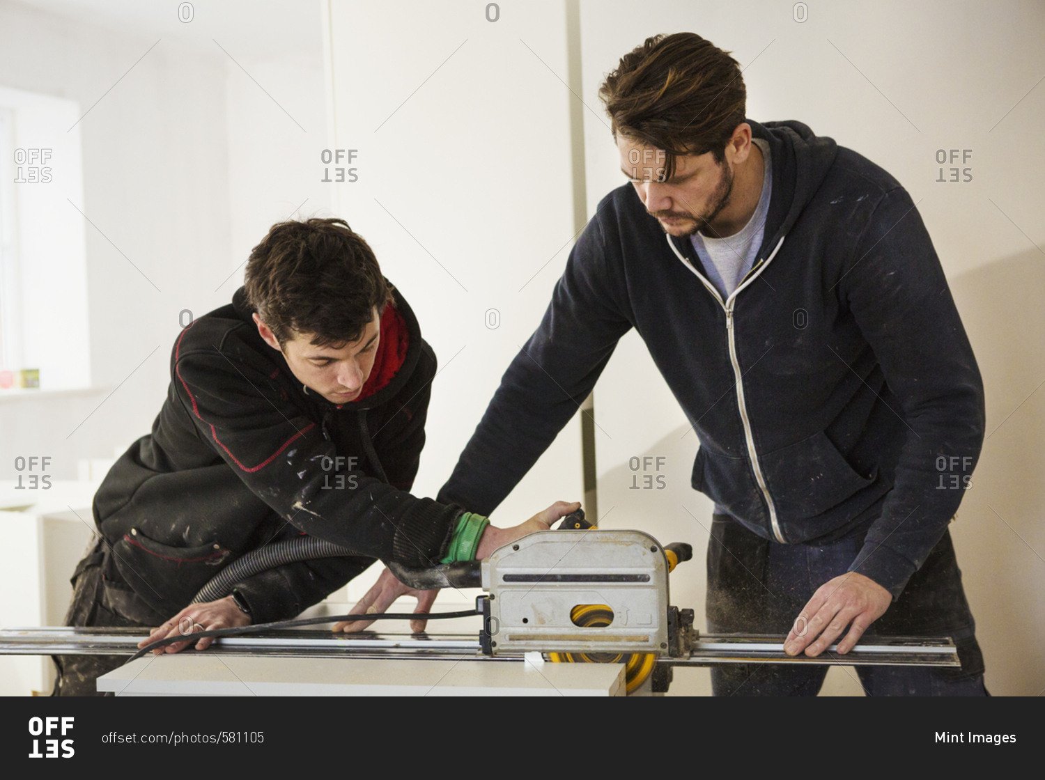 Two builders, cutting plasterboard with a circular saw