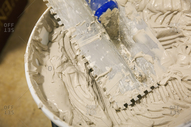 Close up of a tiling trowel and bucket of tile adhesive