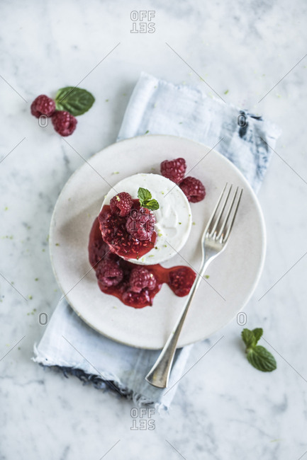 Plate with cheesecake topped with raspberry compote and mint