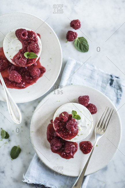 Serving of round cheesecake topped with raspberry compote and mint