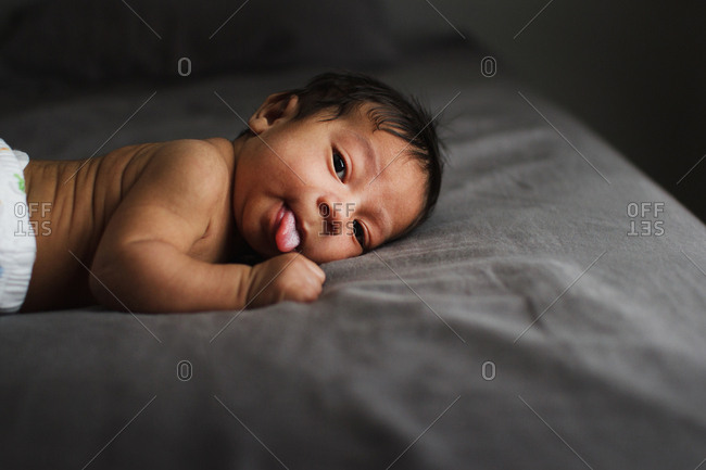 Newborn lying awake on a bed