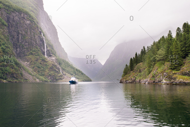 Boat on narrow waterway between forested cliffs