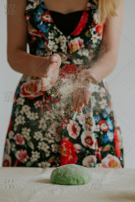 Woman dusting ball of green dough with flour