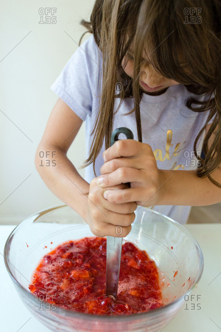 Girl mashing berries for jam