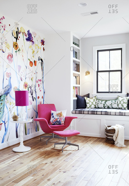 Pink chair and ottoman in a room with colorful animal wallpaper
