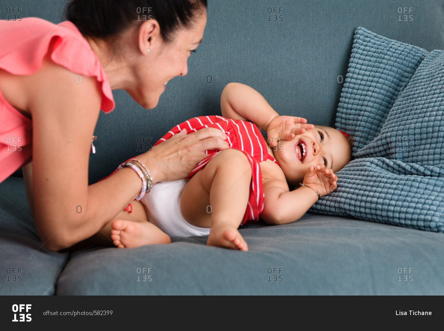 Mom tickling toddler girl on couch