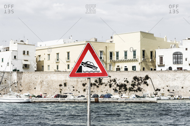 Street sign near the port, danger: car falling in water with danger road sign warning of car falling off bank