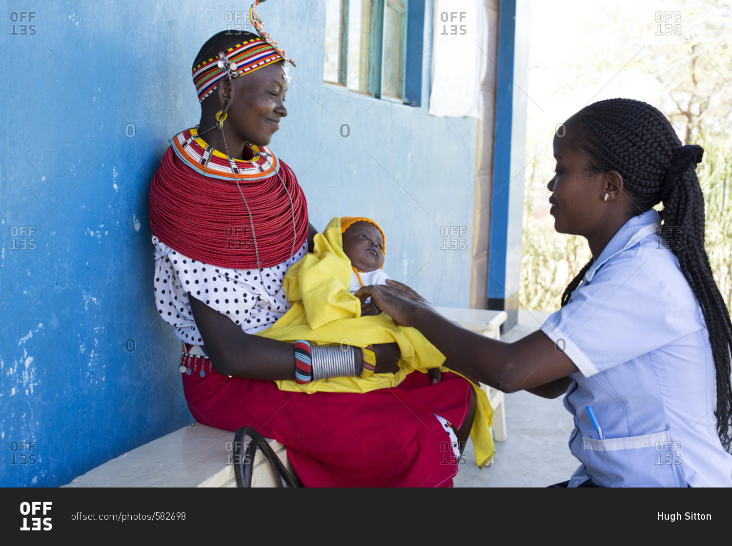 Nurse examining a baby on a mother\'s lap in Kenya, Africa