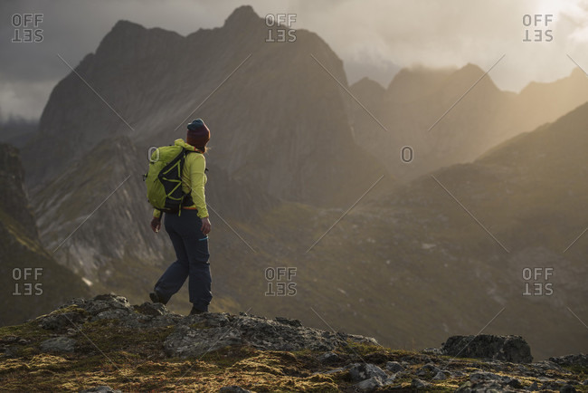 Female hiker on summit of Tverrfjellet with view over distant mountains, Lofoten Islands, Norway