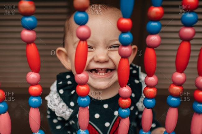 Toddler girl grinning through beads