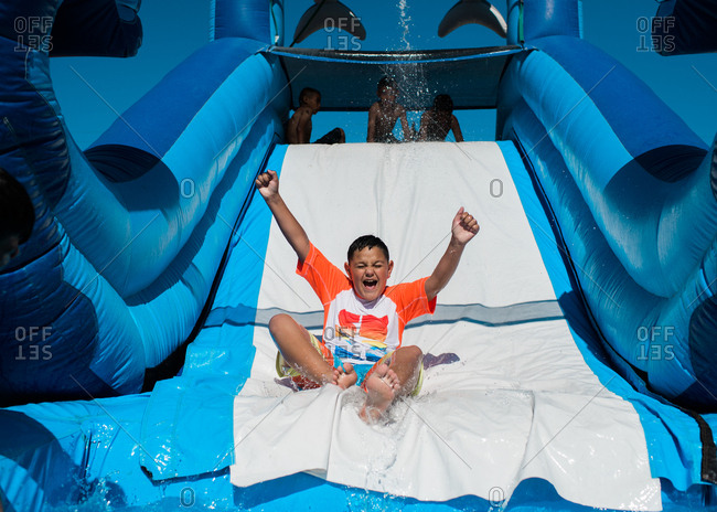 Excited boy going down water slide