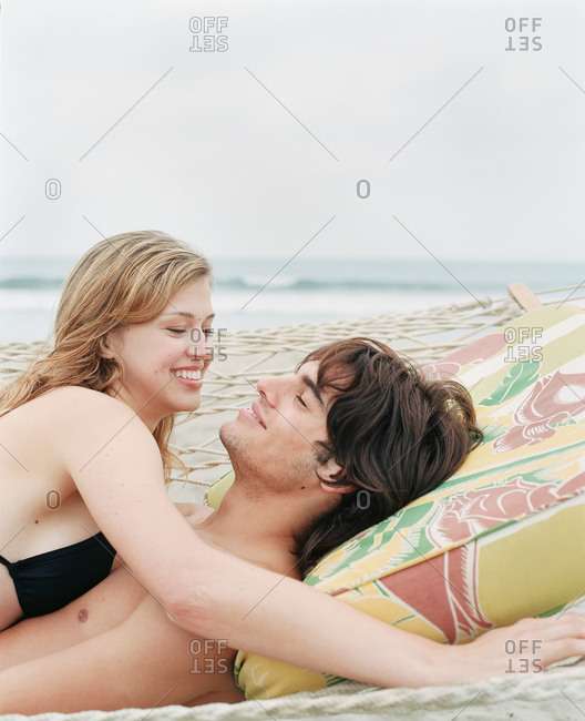 Woman lying on the beach without the bikini top looking at camera