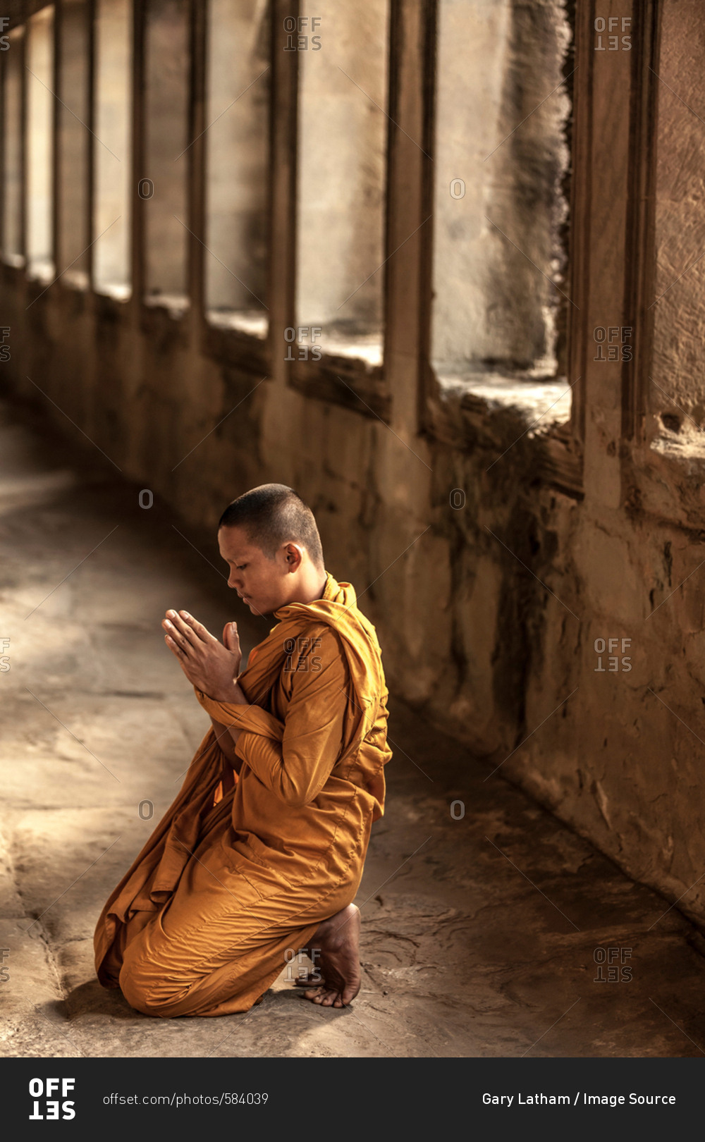 Young Buddhist monk praying in temple, Angkor Wat, Siem Reap, Cambodia