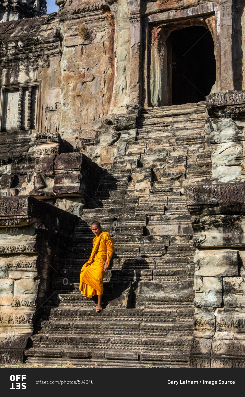 Young Buddhist monk walking down steps at temple in Angkor Wat, Siem Reap, Cambodia