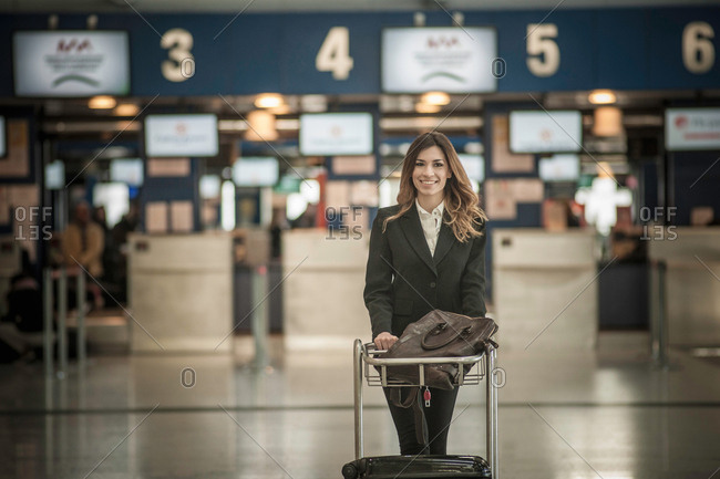 Young woman with luggage trolley in airport
